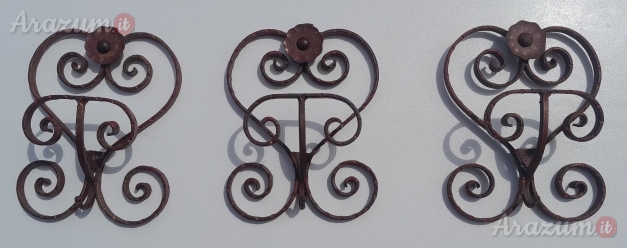 Appendiabiti in ferro battuto con volute decorative e un motivo floreale.